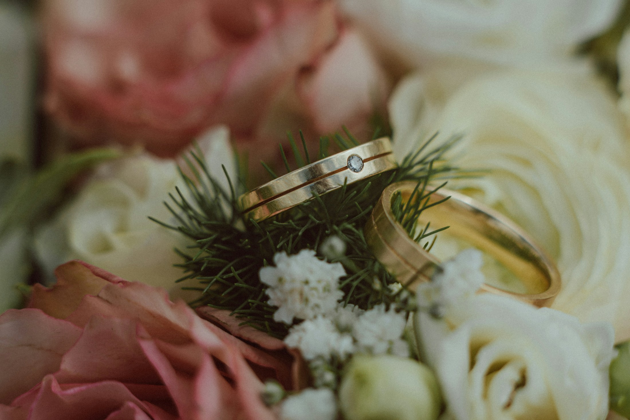 Two gold wedding rings resting on a rose bouquet
